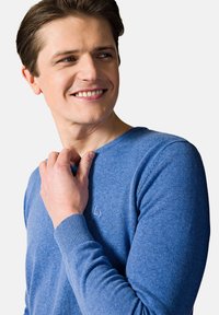 Niebieski dzianinowy sweter z okrągłym dekoltem i ściągaczami. Posiada subtelne logo na piersi. Miękka faktura i lekka konstrukcja.