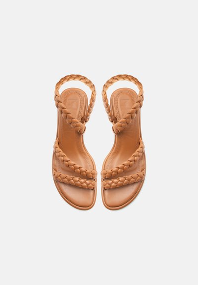 Ταμπά φλατ σανδάλια με τρεις πλεκτές λουρίδες, συμπεριλαμβανομένου ενός γύρω από τον αστράγαλο, σε λευκό φόντο.
