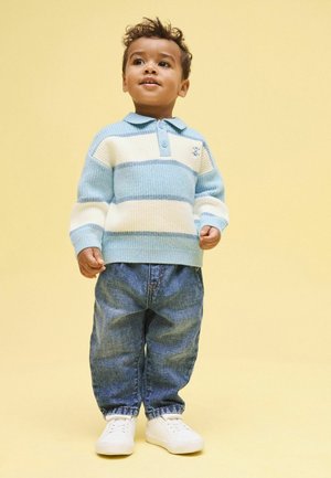 Pulover cu dungi albastre deschis și crem, cu guler, asortat cu blugi din denim largi și pantofi albi. Design simplu și confortabil.