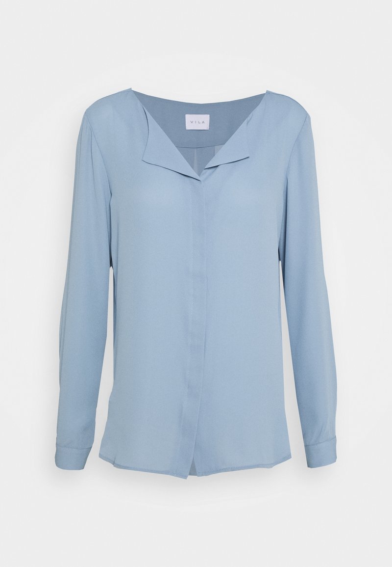 Blouse bleu clair à manches longues avec un col en V sans col, une fermeture à boutons et une texture lisse. Dispose d'un ourlet droit et de fentes latérales.