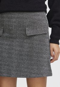 Jupe mini à motif pied-de-poule noir et blanc, featuring deux poches avant, une coupe droite et un tissu tissé texturé.