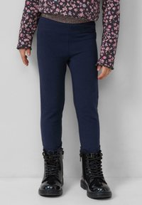 Navy leggings gemaakt van rekbaar katoenmix stof, gecombineerd met glanzende zwarte enkelboots met vetersluiting en ritsen aan de zijkant.