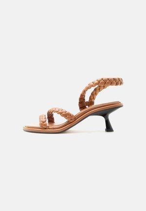 Sandale beige à brides avec des lanières en cuir tressé et un petit talon kitten noir, vue de profil sur fond blanc.