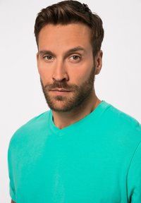T-shirt turchese a scollo a V realizzata in morbido cotone, con maniche corte e una superficie liscia senza motivi o dettagli.