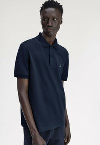 Polo navy in misto cotone, con colletto classico, patta a tre bottoni e logo discreto sul petto. Maniche corte.