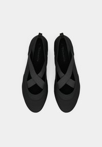 Sapatos pretos tipo slip-on com tiras elásticas cruzadas, bicos arredondados e alças no calcanhar, apresentados numa vista de cima sobre um fundo branco.