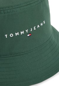 Πράσινο υφασμάτινο καπέλο τύπου bucket με ραφές. Διαθέτει το λογότυπο "TOMMYJEANS" και μικρό τριχρωματικό έμβλημα.