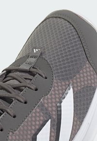 Szare buty sportowe z siateczkowym cholewką, okrągłymi sznurówkami i białymi akcentami. Posiadają wyściółkę przy kołnierzu oraz teksturowane wykończenie materiału.