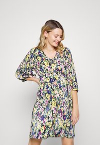 Vestido de maternidade em padrão floral, com detalhes franzidos, decote em V e mangas três quartos. Apresenta cores vivas como amarelo, rosa e azul.