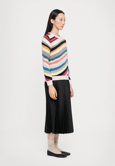Maglione a righe multicolore con maniche corte, abbinato a una gonna plissettata nera, calzini beige e ballerine nere. Texture liscia, design casual.