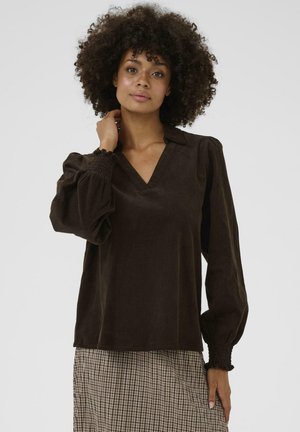 Blusa in corduroy marrone con scollatura a V, maniche a palloncino e polsini arricciati. Caratterizzata da una texture liscia e una vestibilità comoda.