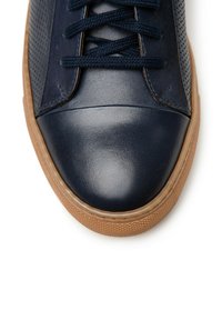 Granatowe trampki z gładkim skórzanym noskiem, teksturowanymi bocznymi panelami i okrągłymi sznurowadłami. Posiadają gumową podeszwę i subtelny perforowany wzór.