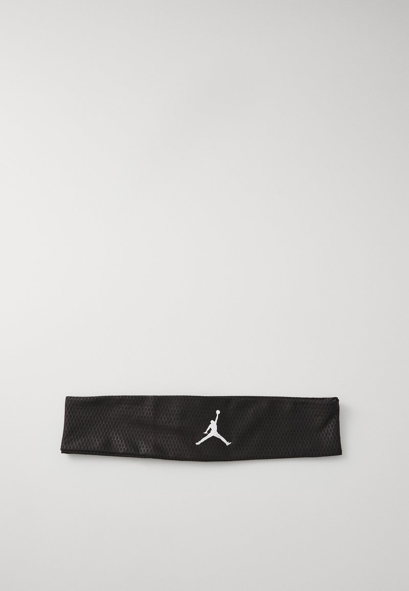 Juodas tinklinis plaukų raištis su baltu Jumpman logotipu. Dizainas plokščias, su tekstūruota paviršiumi ir horizontaliu pavidalu, tinkamas sportui.