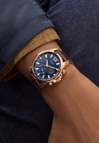 Orologio cronografo con quadrante blu, cassa in oro rosa e cinturino in pelle marrone. Le caratteristiche includono grandi indici delle ore e due sottodial.