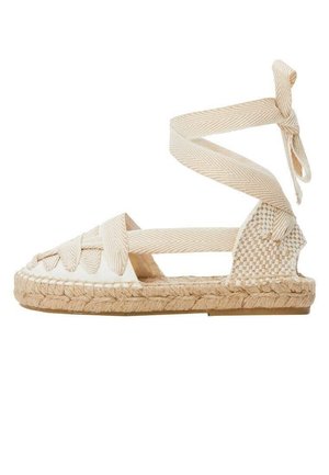 Sandale espadrille plate beige avec semelle en jute tissée, brides croisées en tissu et long lien à nouer autour de la cheville.