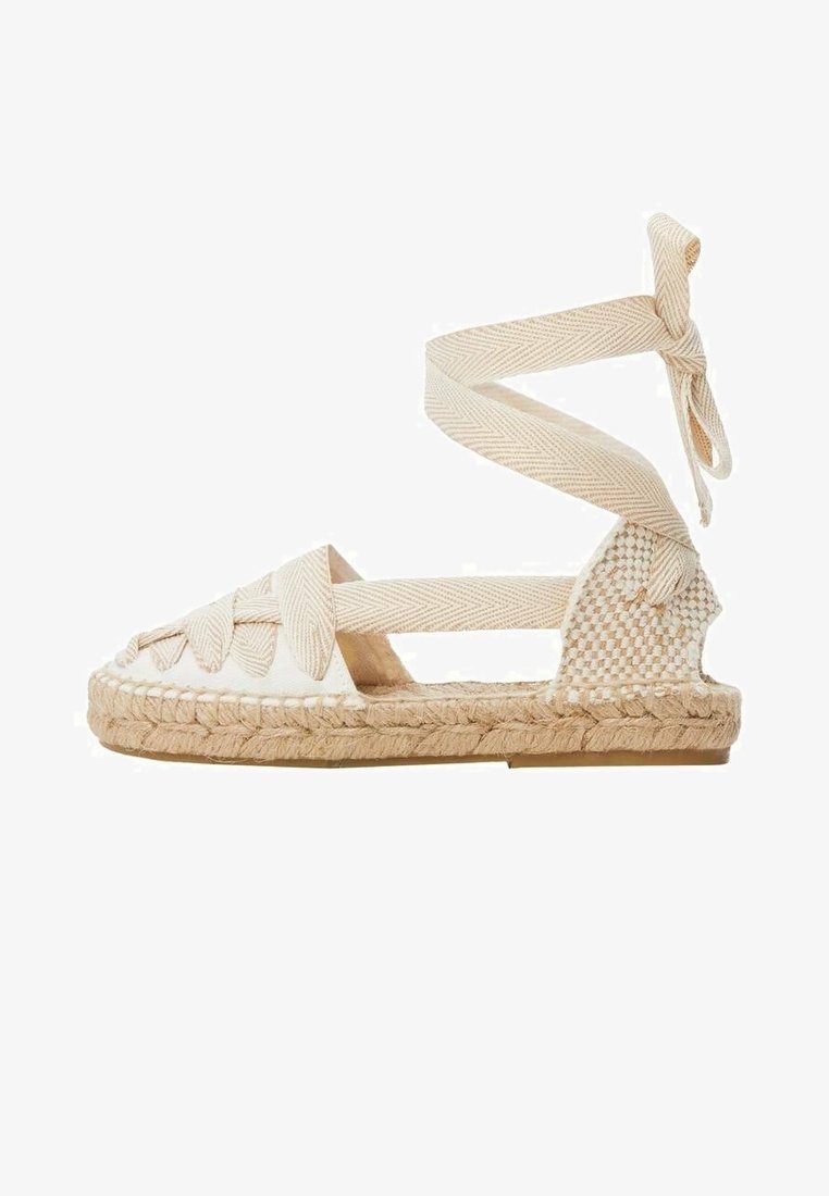 Sandale espadrille plate beige avec semelle en jute tissée, brides croisées en tissu et long lien à nouer autour de la cheville.