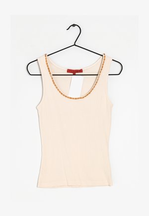 Beige geribd tanktop aan een zwarte hanger, met een ronde halslijn versierd met kleine, rechthoekige, lichtbruine decoratieve accenten.