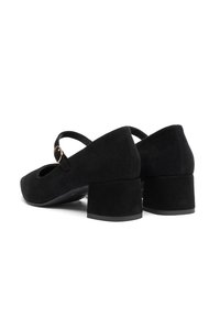 Black suede Mary Jane shoes with a rounded toe, mid-height block heel, and an adjustable strap featuring a gold-tone buckle detail.