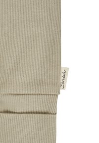 Beige Rippstrick-Leggings mit glatter Textur und einem kleinen Markenetikett. Verfügt über ein schmal zulaufendes Design an den Knöcheln.