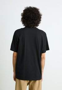 Black cotton t-shirt with a loose fit, round neckline, and short sleeves. Simple design, no visible patterns or graphics.