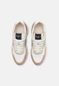 Hvite og beige sneakers med grå detaljer, som har en teksturert såle, rund tå, snøring og en logo på tungen.