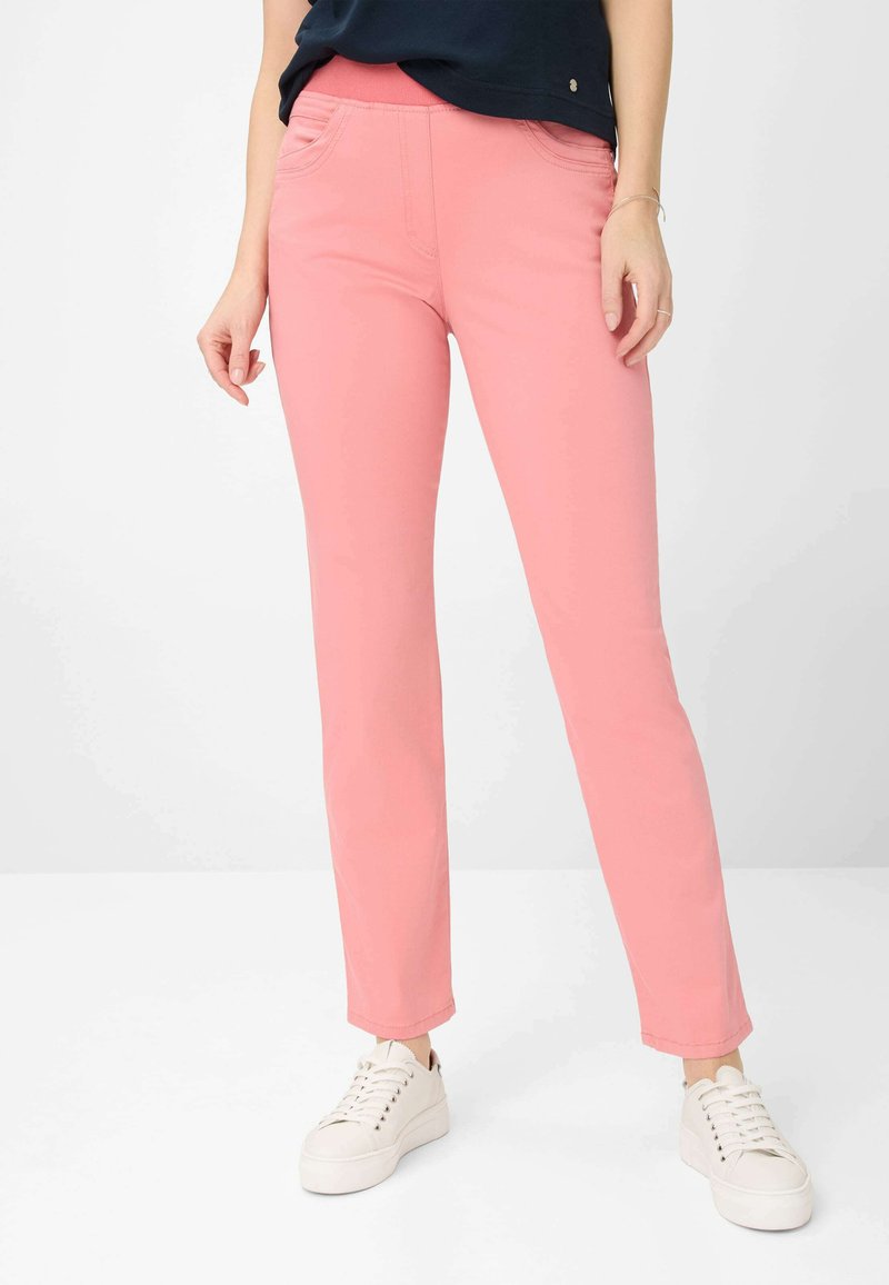 Rosa Stretch-Hosen mit Slim-Fit, ausgestattet mit Fronttaschen und einer glatten Stoffstruktur, kombiniert mit weißen Sneakers.