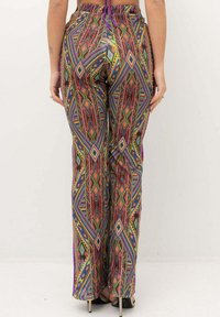 Pantaloni a fantasia colorati con un design geometrico in vivaci tonalità di rosso, blu, verde e giallo; vestibilità ampia e stile a gamba lunga.
