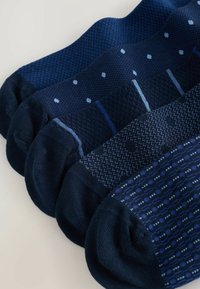 Five pairs of navy blue men's ankle socks with different patterns aligned side by side on a light surface.