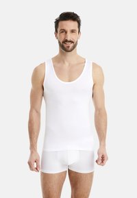White cotton tank top with a round neckline, side straps, and matching white boxer shorts. Fabric appears smooth and fitted.