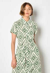 Grünes und cremefarbenes Muster-Kleid mit Kragen, kurzen Ärmeln und gebundener Taille sowie Knopfleiste.