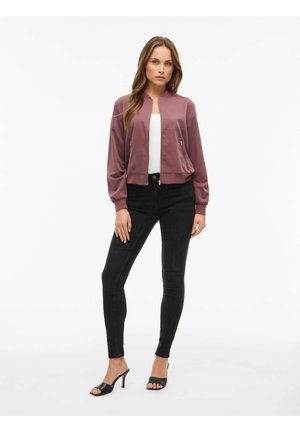 Giubbotto bomber in satin mauve chiaro, con zip frontale, polsini a costine e due tasche con zip. Abbinato a jeans skinny neri e tacchi aperti.