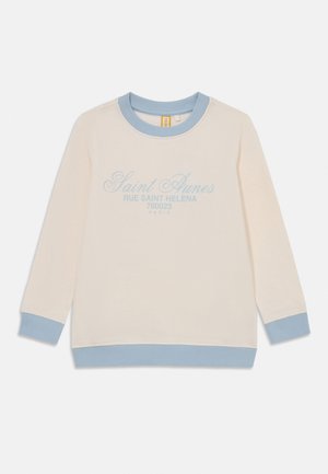 Kreemjas pikkade varrukatega dressipluus helesinise soonikkoega krae, mansettide ja äärega, millel on ees kiri "Saint Aunes Rue Saint Helena 760023 Paris".