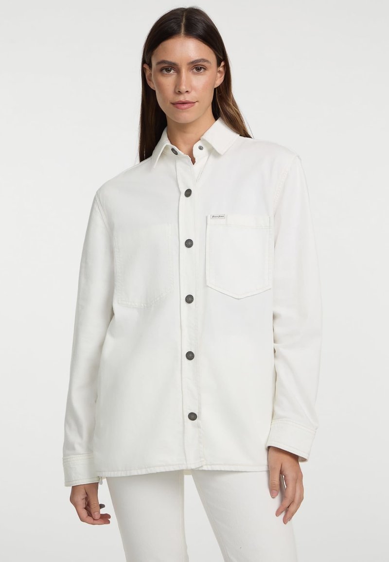Witte denimbloes met lange mouwen, knopen aan de voorkant, twee borstzakken en zwarte knopen. Glad textuur en ontspannen pasvorm.