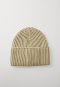 Beige ribbestrikket lue med brett, vist liggende flat på en hvit bakgrunn.