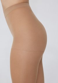 Collants nude transparents avec une texture lisse, une taille sans couture et une forme ajustée, couvrant la jambe jusqu'à mi-cuisse.