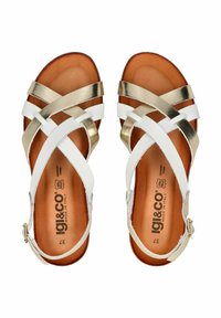 Sandalias de tiras cruzadas en blanco y oro metálico con una plantilla de cuero marrón, que cuentan con una hebilla ajustable en el tobillo y acentos texturizados.