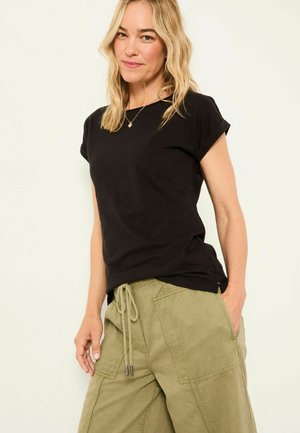 Black short-sleeve T-shirt with rolled cuffs, lightweight fabric, paired with loose olive-green cargo pants featuring drawstring waist and pockets.