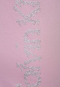 Tela rosa con adornos de rhinestones plateados dispuestos en un patrón de texto estilizado. Textura suave, diseño casual.