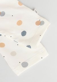 Tissu en coton crème avec une variété de pois bleu clair, terre cuite et gris. Texture lisse et bords cousus.