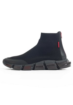 Czarny, wysokostronny sneaker w formie skarpety z prążkowanym dzianym mankietem, grubą segmentowaną podeszwą, czerwonym suwakiem i małą czerwoną metką z boku.