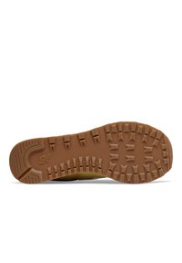 Semelle en caoutchouc beige avec des profondeurs de crampons pour une meilleure traction. Présente une surface texturée et le logo New Balance bien en vue dans la zone du talon.