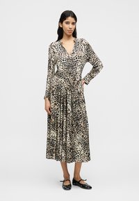 Robe à manches longues à imprimé animalier, avec un décolleté en V profond, une taille cintrée avec une ceinture assortie, un tissu fluide et une coupe longueur cheville.