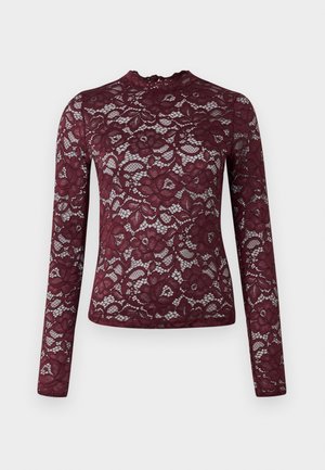 Top in pizzo bordeaux a maniche lunghe con motivi floreali e colletto alto su sfondo bianco.