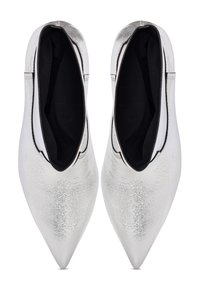 Zapatos de punta plateada con un acabado metálico, aberturas elásticas y forro interior negro, que presentan una textura suave y un diseño elegante.