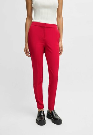 Rode op maat gemaakte broek van rekbaar materiaal, met een slank design, slim fit en minimale details. Gemaakt in combinatie met zwarte loafers.
