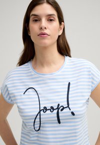 Blauwe en witte gestreepte t-shirt met een ronde hals en korte mouwen. Bevat een bold zwarte geborduurde tekst "Joop!" op de voorkant.