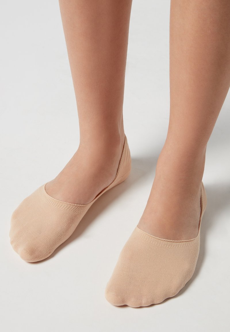 Calze beige basse con texture a costine e punta arrotondata, progettate per coprire solo il piede, con una finitura liscia.
