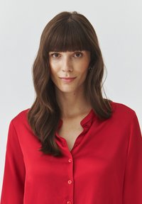 Red satin blouse with a button-up front, long sleeves, and a soft, smooth texture. Features a classic collar and glossy buttons.