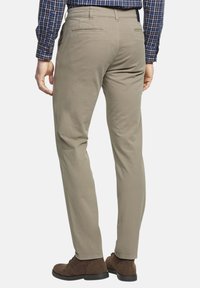 Beige katoenen broek met een rechte pijp, met achterzakken en gestikte details, gecombineerd met bruine suède schoenen.