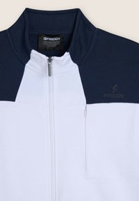 Chaqueta ligera de hombre con esquema de colores en azul marino y blanco. Cuenta con un cuello alto, cremallera completa y un pequeño bolsillo en el pecho con cremallera.